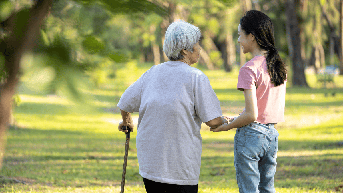 杖を持って散歩する高齢女性と孫娘